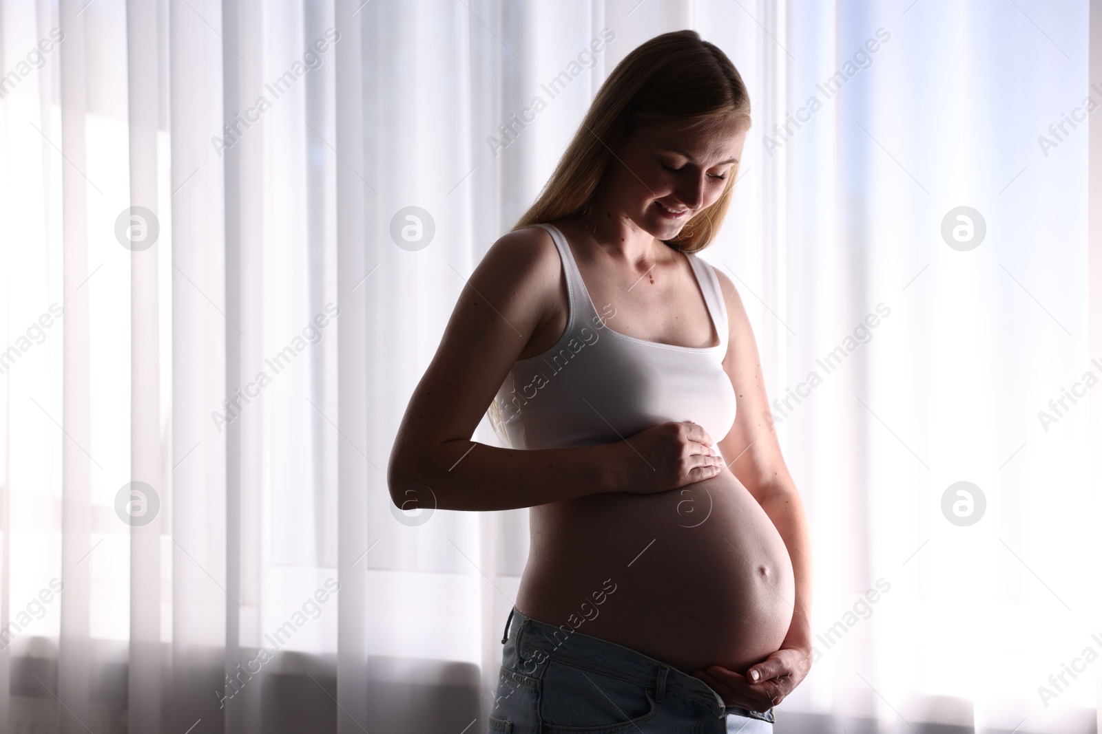 Beautiful pregnant woman near window at home Photo of Beautiful pregnant woman near window at home