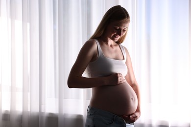 Photo of Beautiful pregnant woman near window at home