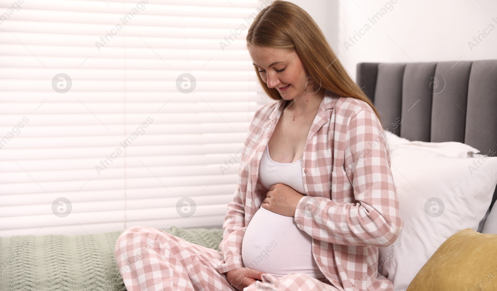 Photo of Beautiful pregnant woman on bed at home. Space for text