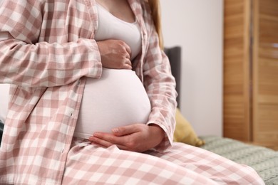 Photo of Beautiful pregnant woman on bed at home, closeup