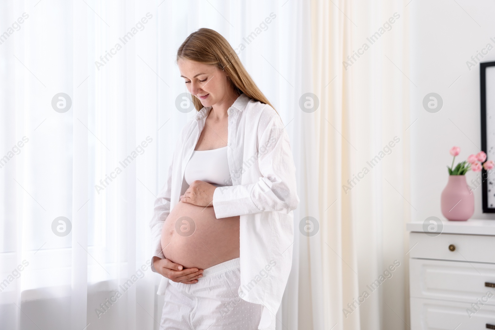 Beautiful pregnant woman touching her belly at home Photo of Beautiful pregnant woman touching her belly at home