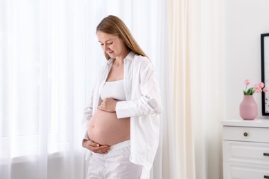 Photo of Beautiful pregnant woman touching her belly at home