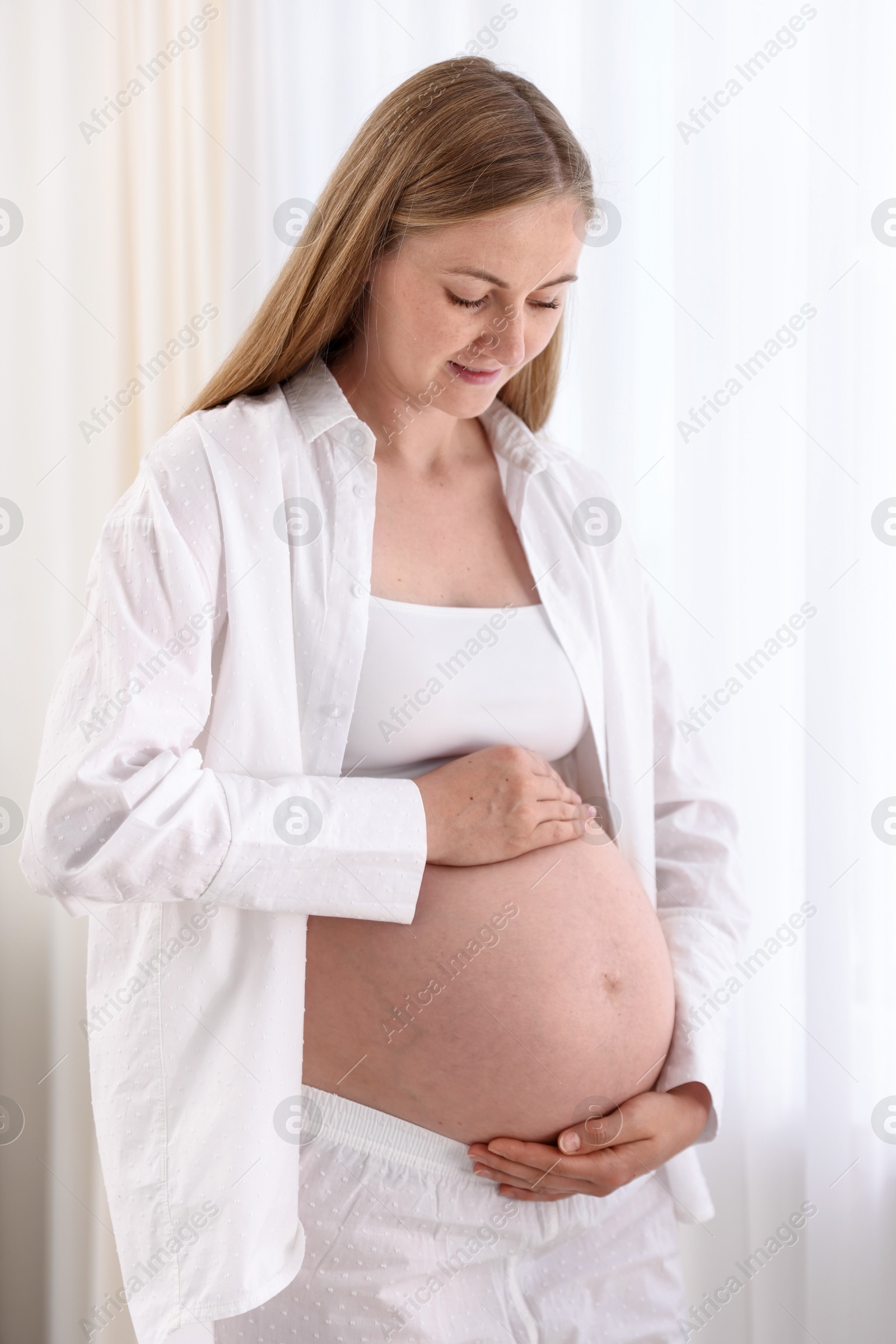 Beautiful pregnant woman touching her belly at home Photo of Beautiful pregnant woman touching her belly at home