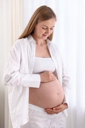 Photo of Beautiful pregnant woman touching her belly at home