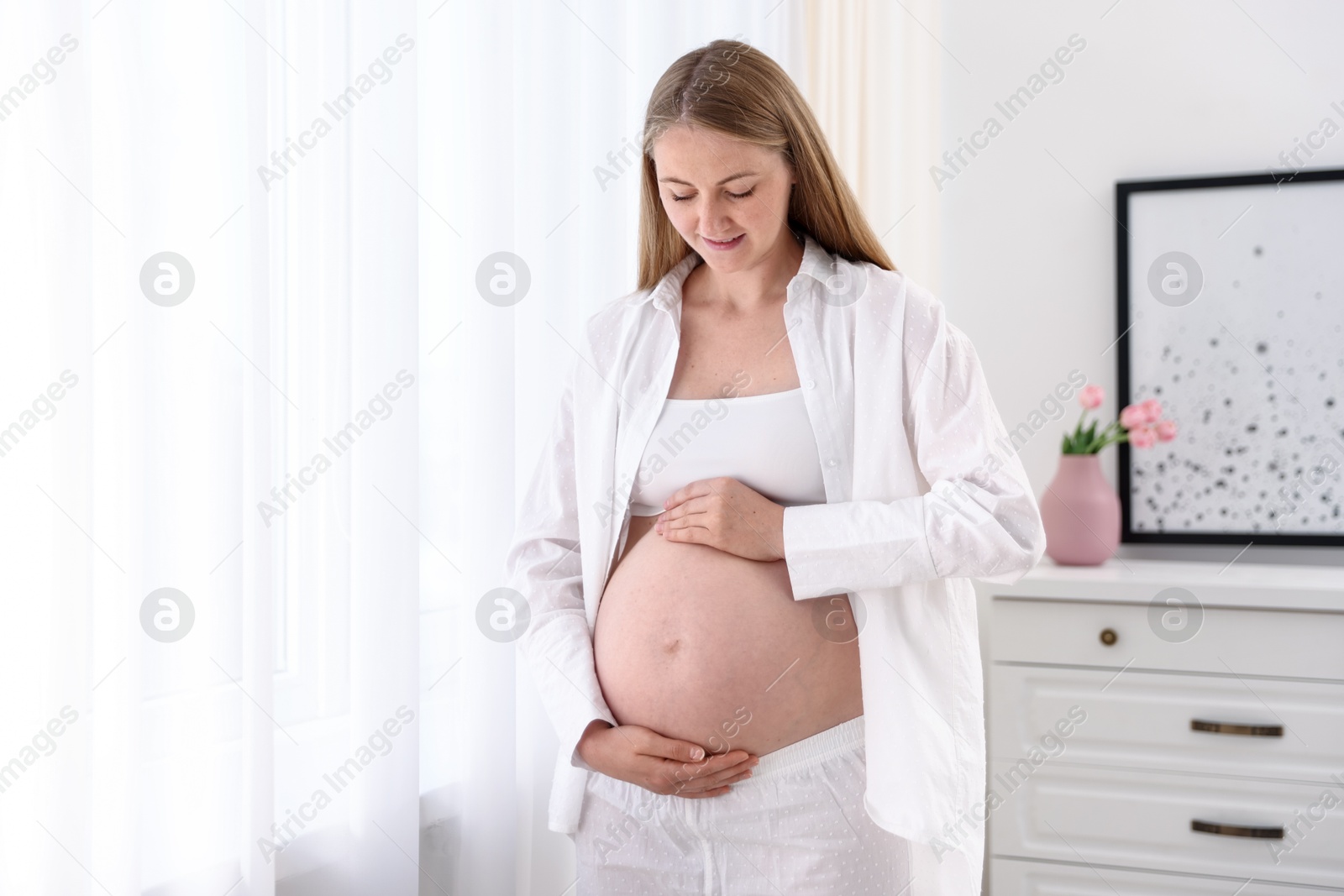 Beautiful pregnant woman touching her belly at home Photo of Beautiful pregnant woman touching her belly at home