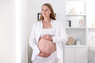 Photo of Beautiful pregnant woman touching her belly at home