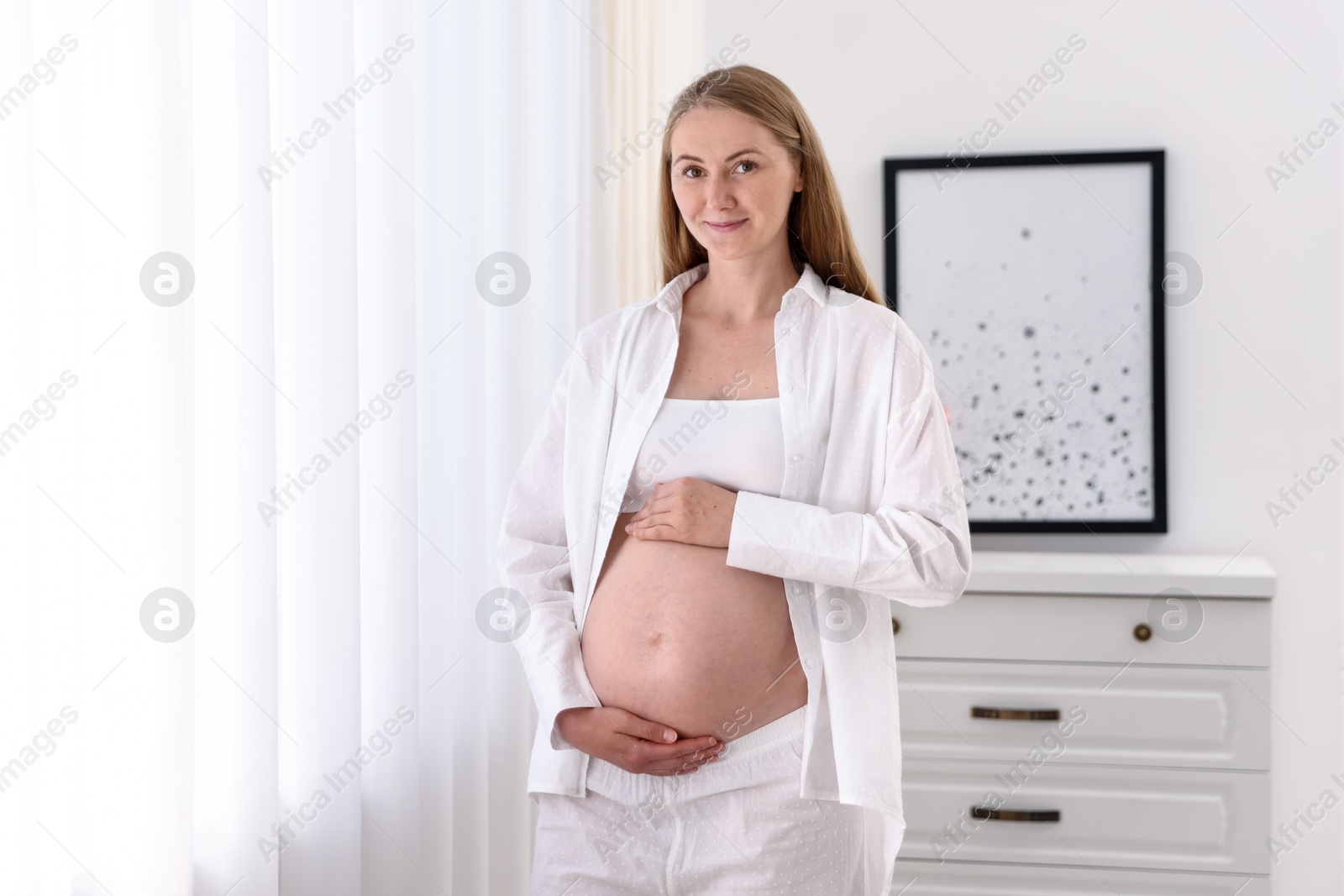 Beautiful pregnant woman touching her belly at home. Space for text Photo of Beautiful pregnant woman touching her belly at home. Space for text