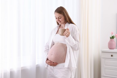 Photo of Beautiful pregnant woman with cup of drink at home