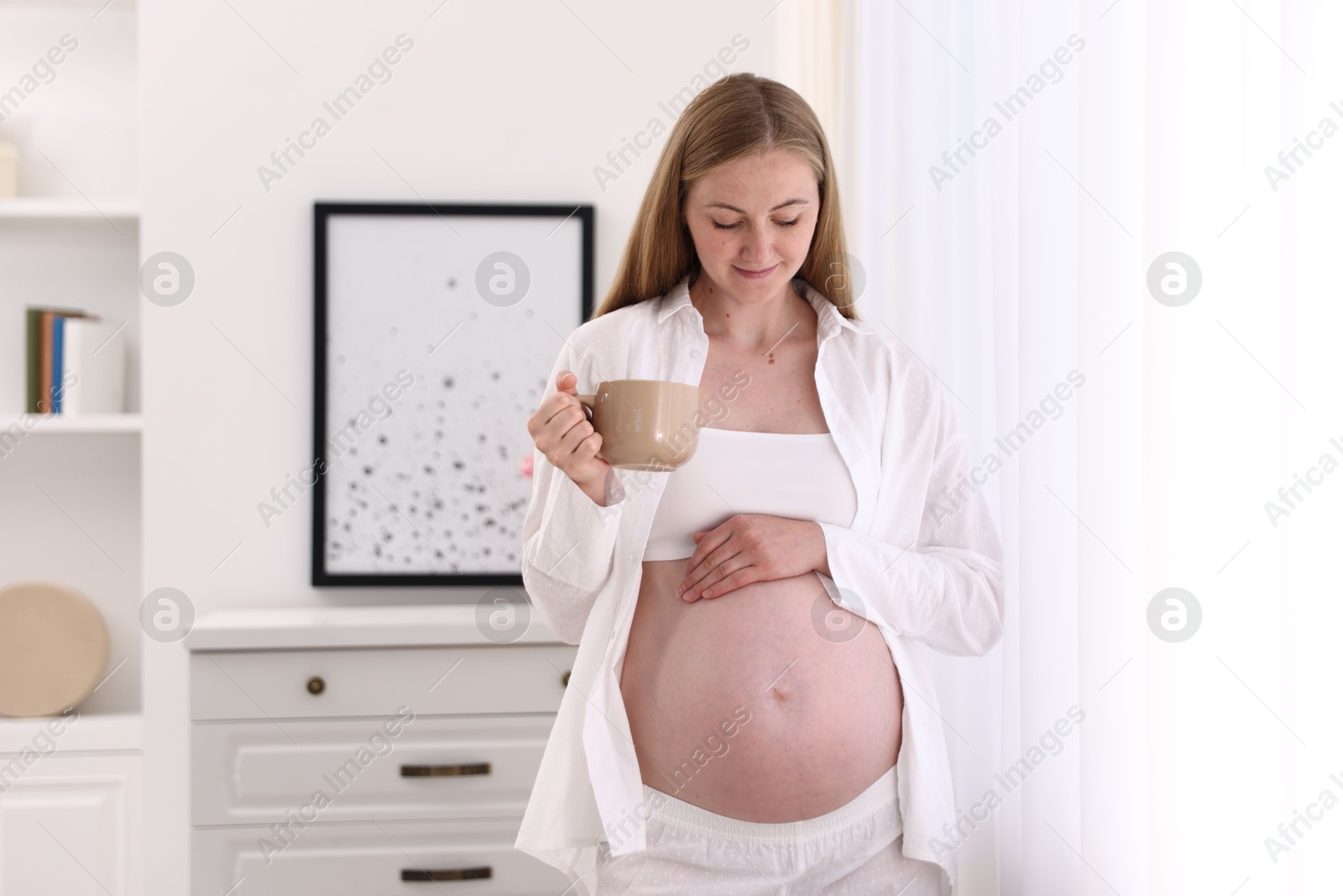 Photo of Beautiful pregnant woman with cup of drink at home