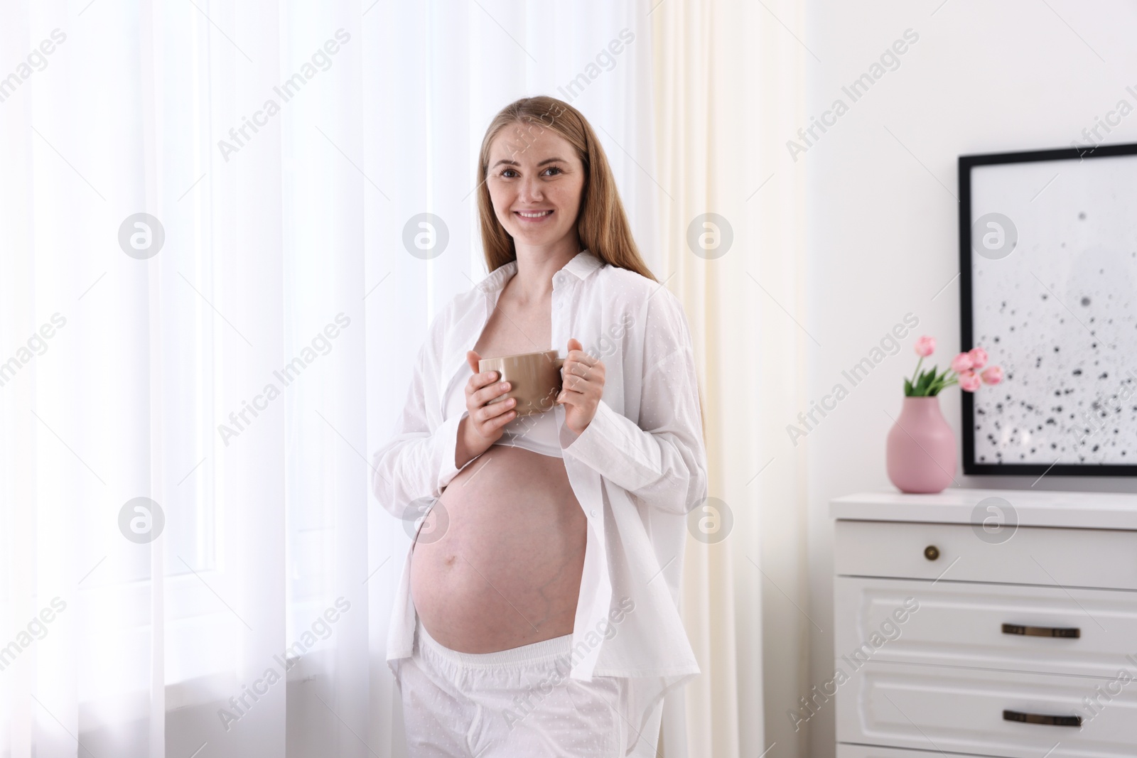 Beautiful pregnant woman with cup of drink at home Photo of Beautiful pregnant woman with cup of drink at home