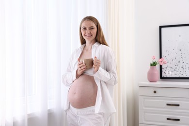 Photo of Beautiful pregnant woman with cup of drink at home