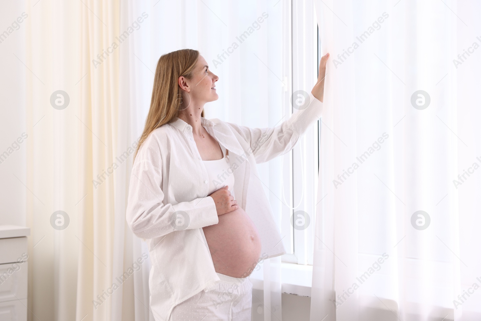 Beautiful pregnant woman near window at home Photo of Beautiful pregnant woman near window at home