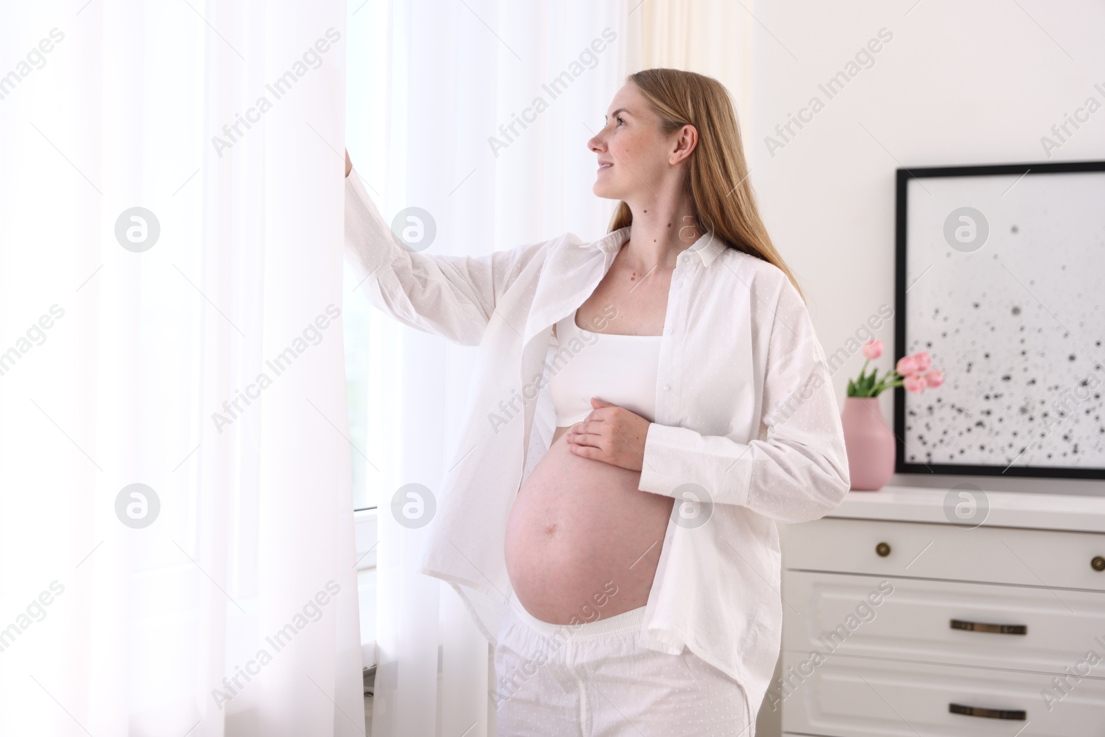 Beautiful pregnant woman near window at home Photo of Beautiful pregnant woman near window at home