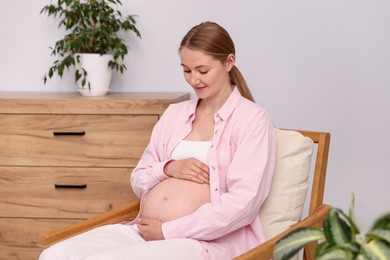 Photo of Beautiful pregnant woman in armchair at home