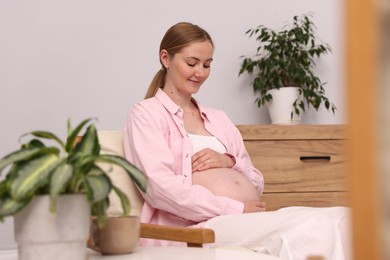 Photo of Beautiful pregnant woman in armchair at home