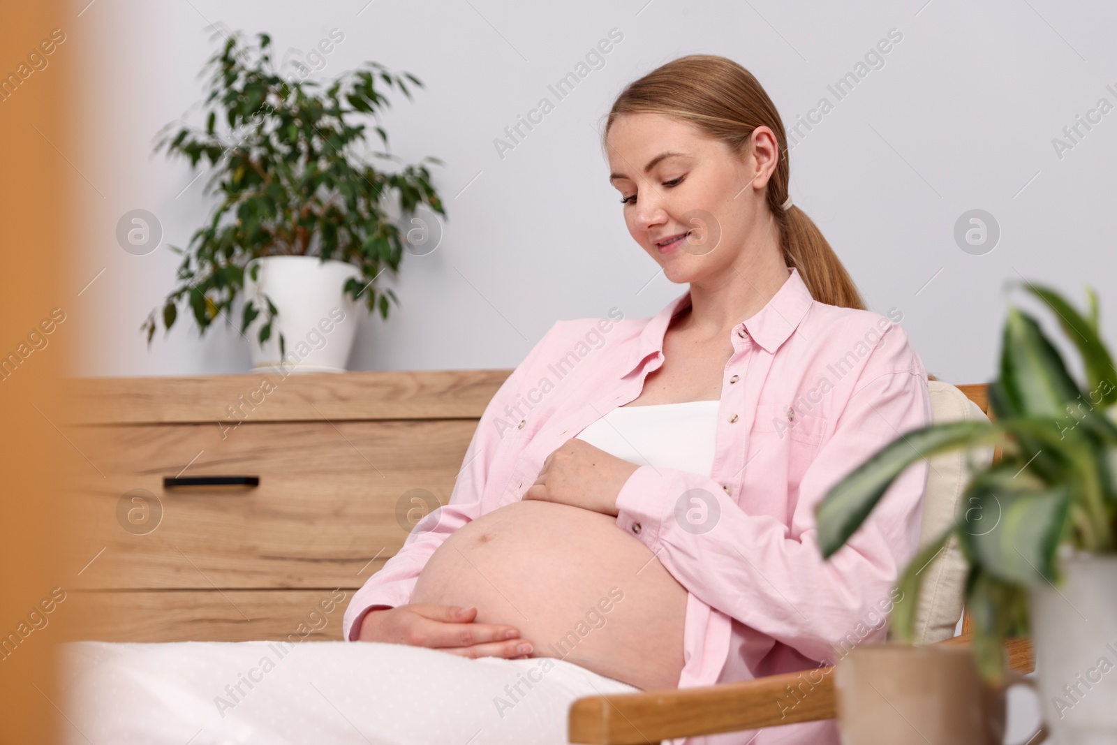 Beautiful pregnant woman in armchair at home Photo of Beautiful pregnant woman in armchair at home