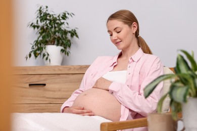 Photo of Beautiful pregnant woman in armchair at home