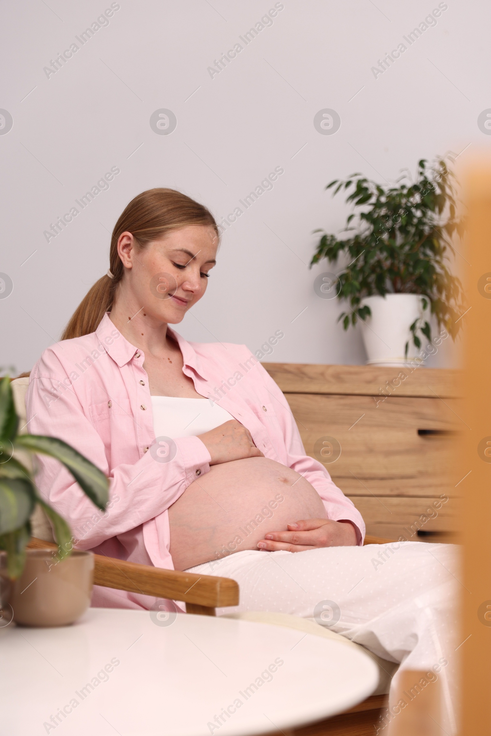Beautiful pregnant woman in armchair at home Photo of Beautiful pregnant woman in armchair at home