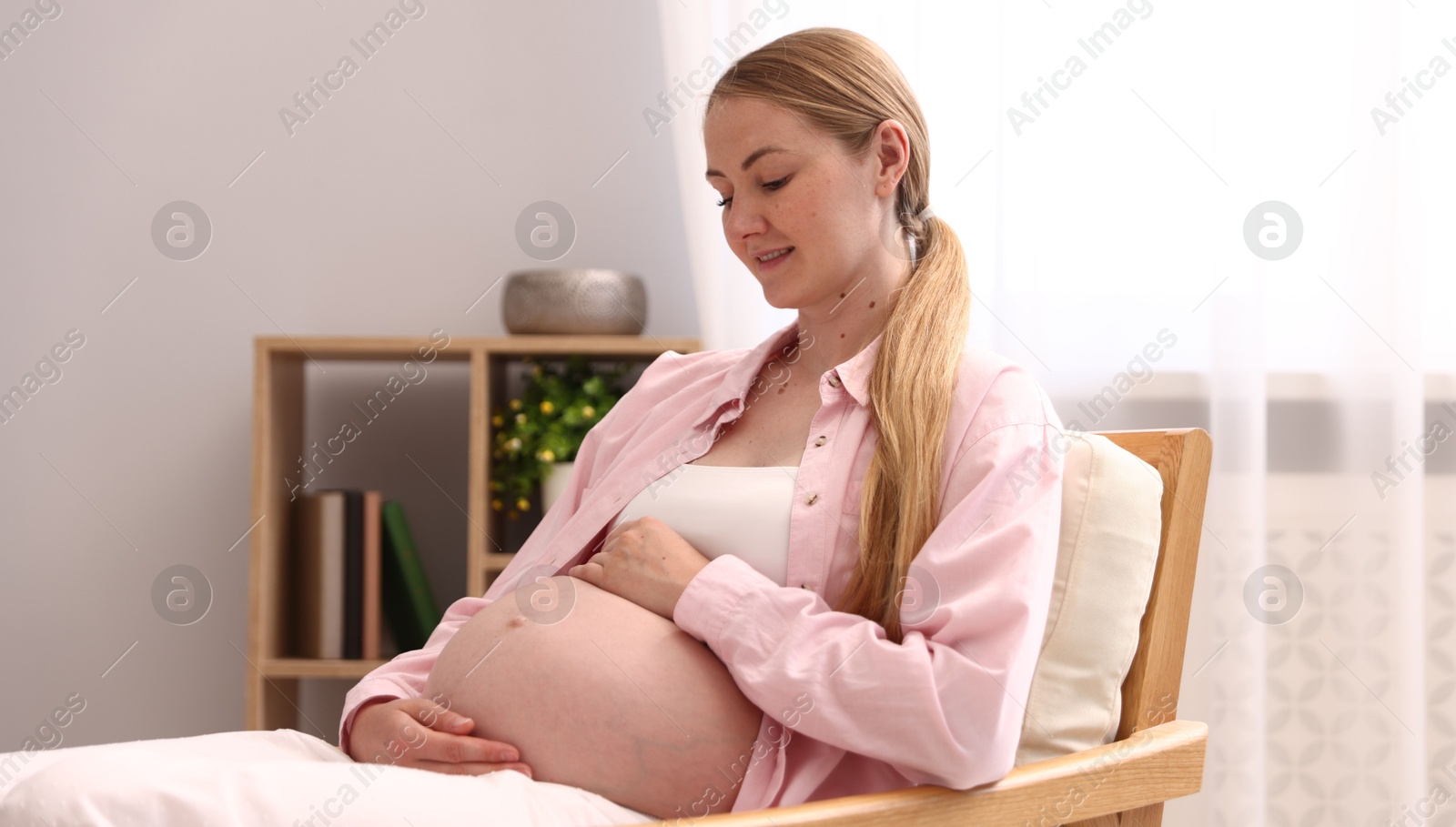 Beautiful pregnant woman in armchair at home Photo of Beautiful pregnant woman in armchair at home