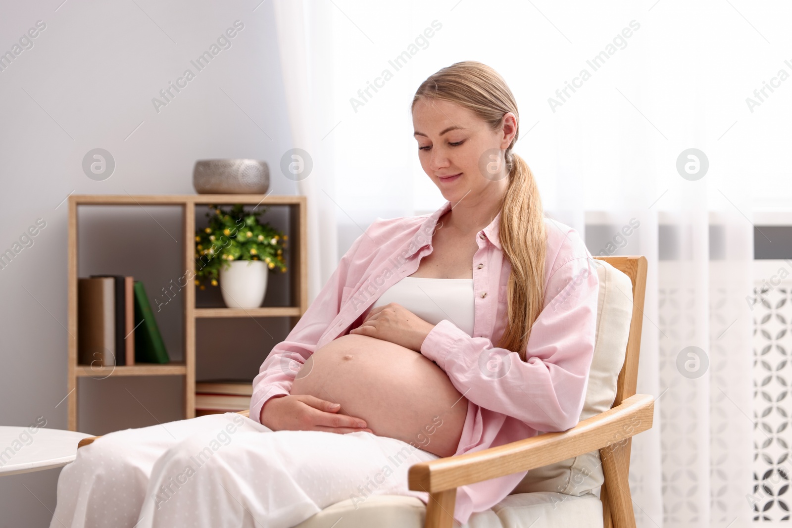 Beautiful pregnant woman in armchair at home Photo of Beautiful pregnant woman in armchair at home