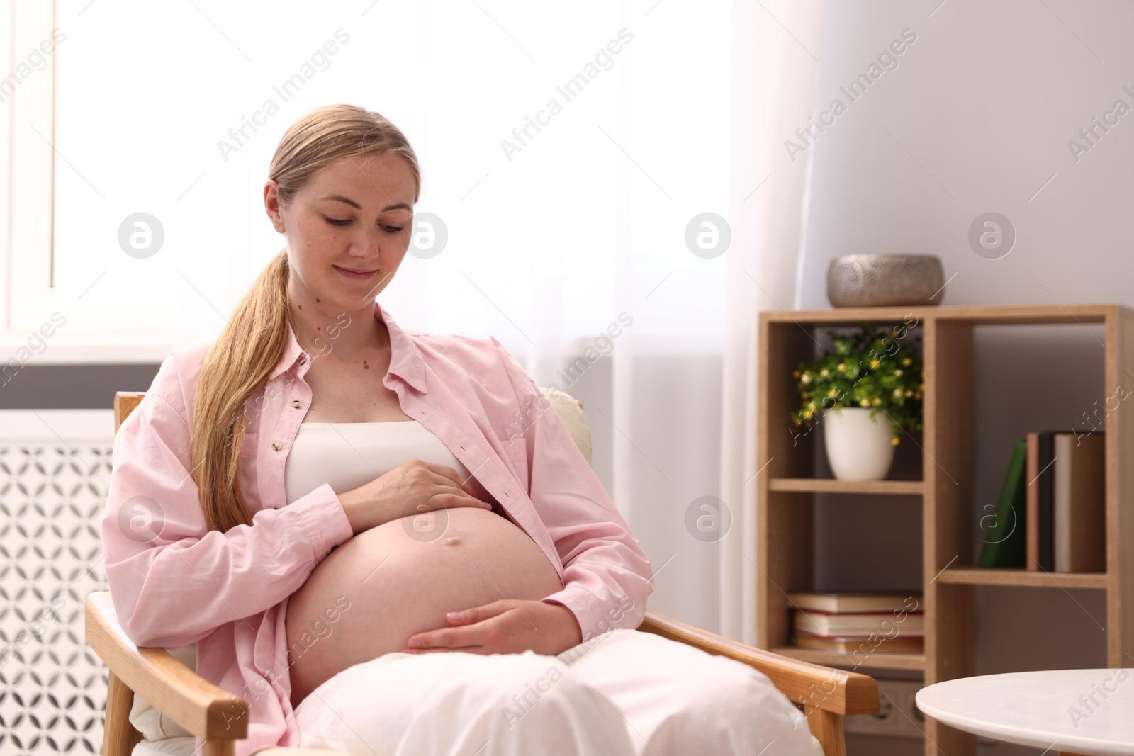 Beautiful pregnant woman in armchair at home. Space for text Photo of Beautiful pregnant woman in armchair at home. Space for text