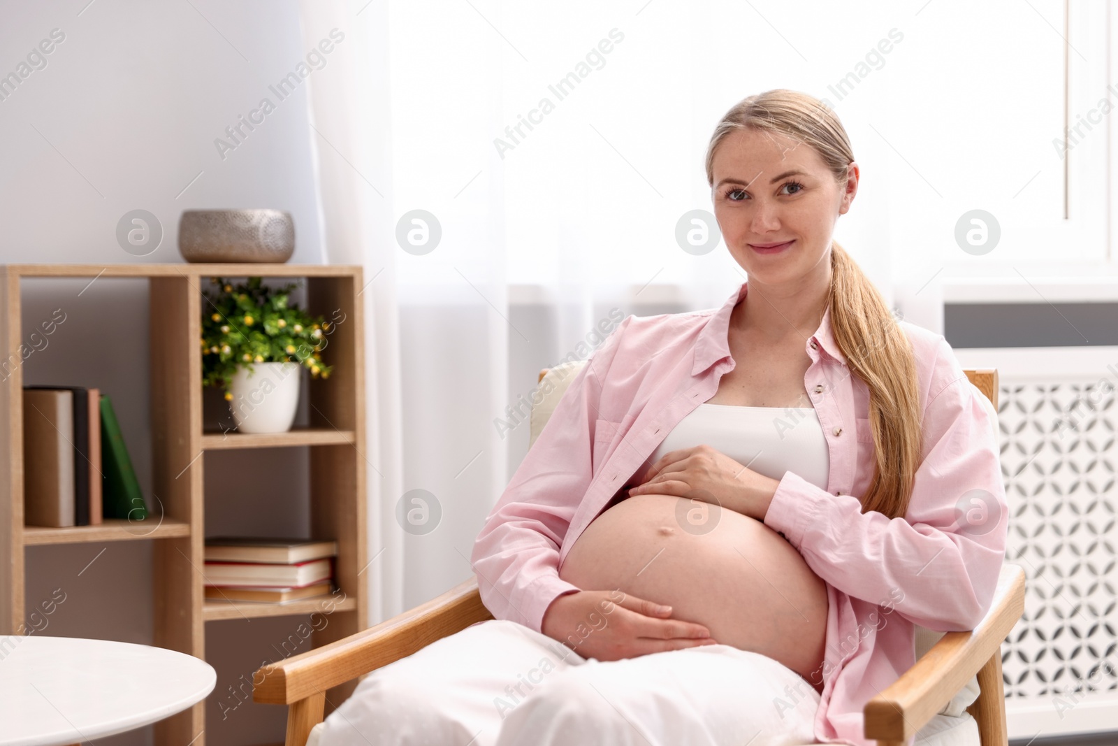 Beautiful pregnant woman in armchair at home. Space for text Photo of Beautiful pregnant woman in armchair at home. Space for text
