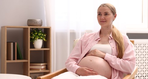 Photo of Beautiful pregnant woman in armchair at home. Space for text