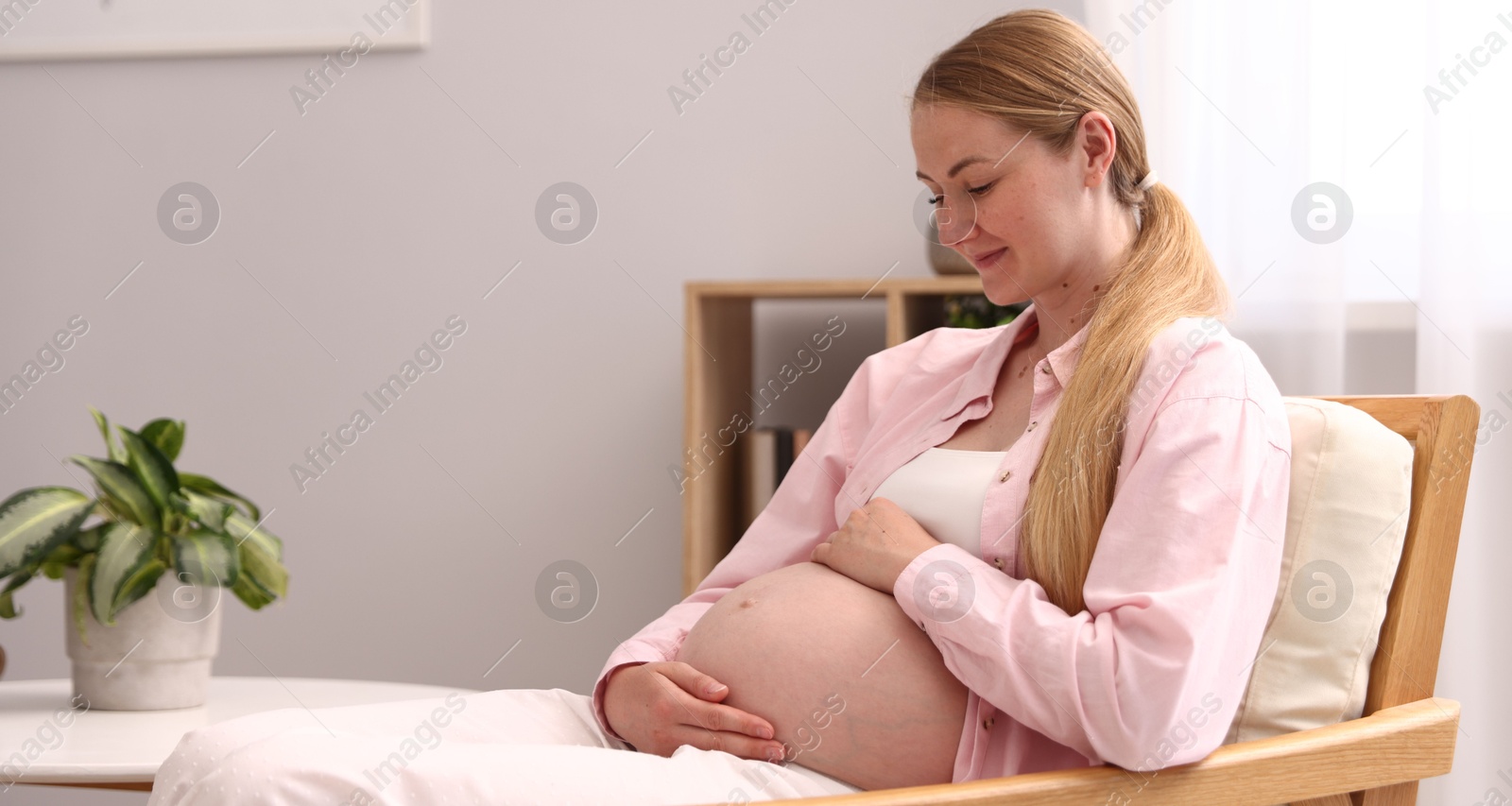 Beautiful pregnant woman in armchair at home. Space for text Photo of Beautiful pregnant woman in armchair at home. Space for text