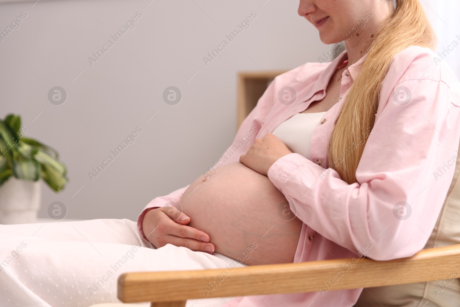 Beautiful pregnant woman in armchair at home, closeup. Space for text Photo of Beautiful pregnant woman in armchair at home, closeup. Space for text