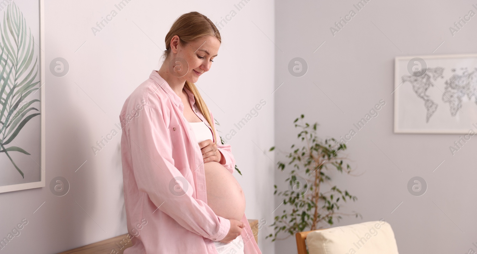 Beautiful pregnant woman touching her belly at home. Space for text Photo of Beautiful pregnant woman touching her belly at home. Space for text