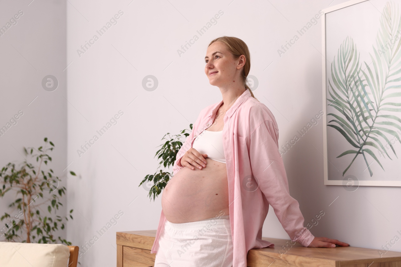Beautiful pregnant woman touching her belly at home Photo of Beautiful pregnant woman touching her belly at home