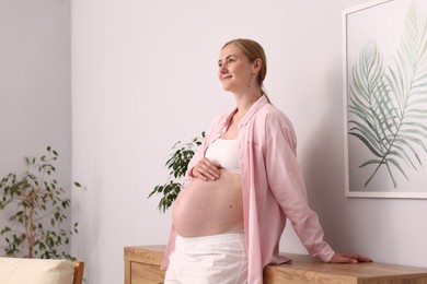 Photo of Beautiful pregnant woman touching her belly at home