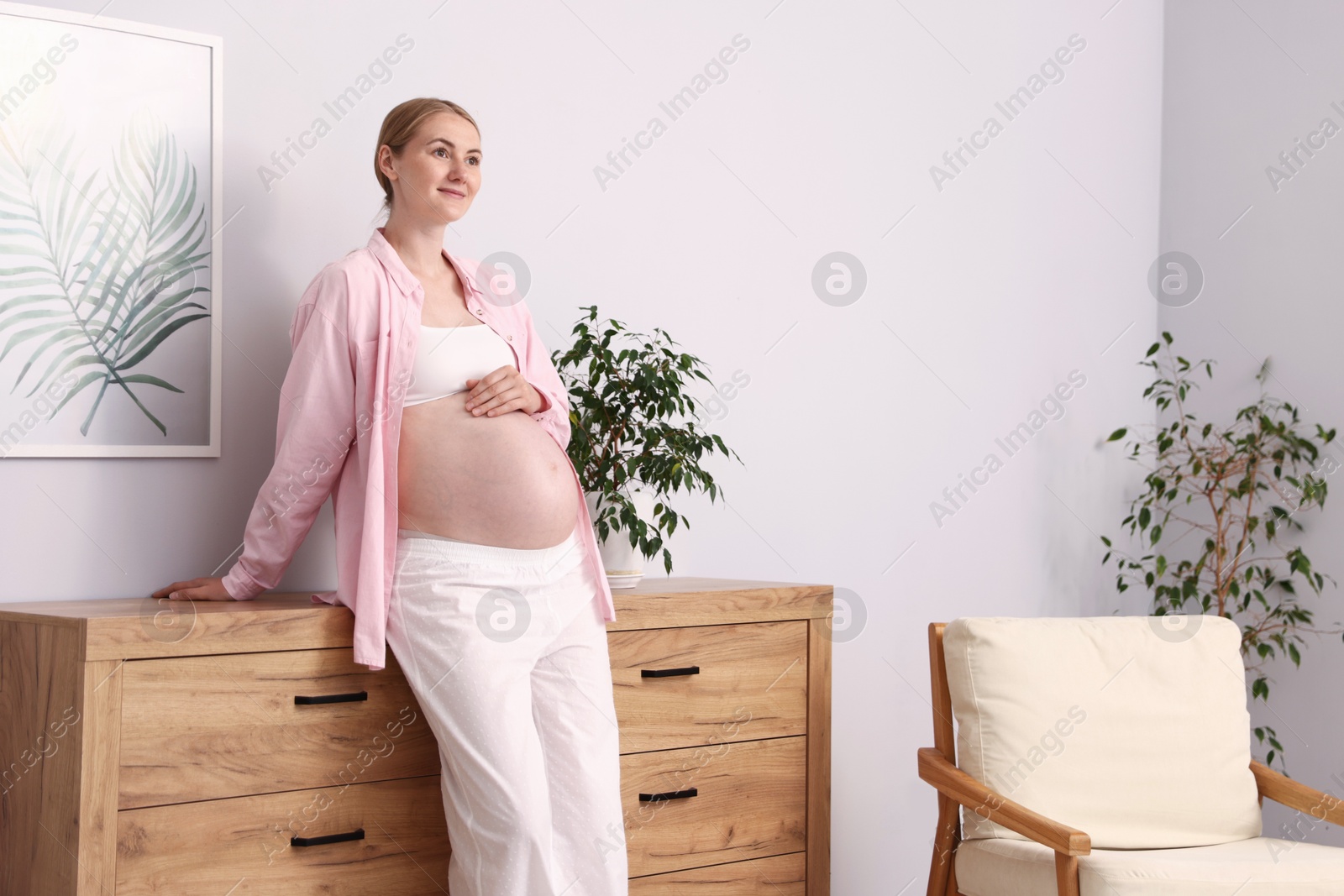 Beautiful pregnant woman touching her belly at home. Space for text Photo of Beautiful pregnant woman touching her belly at home. Space for text