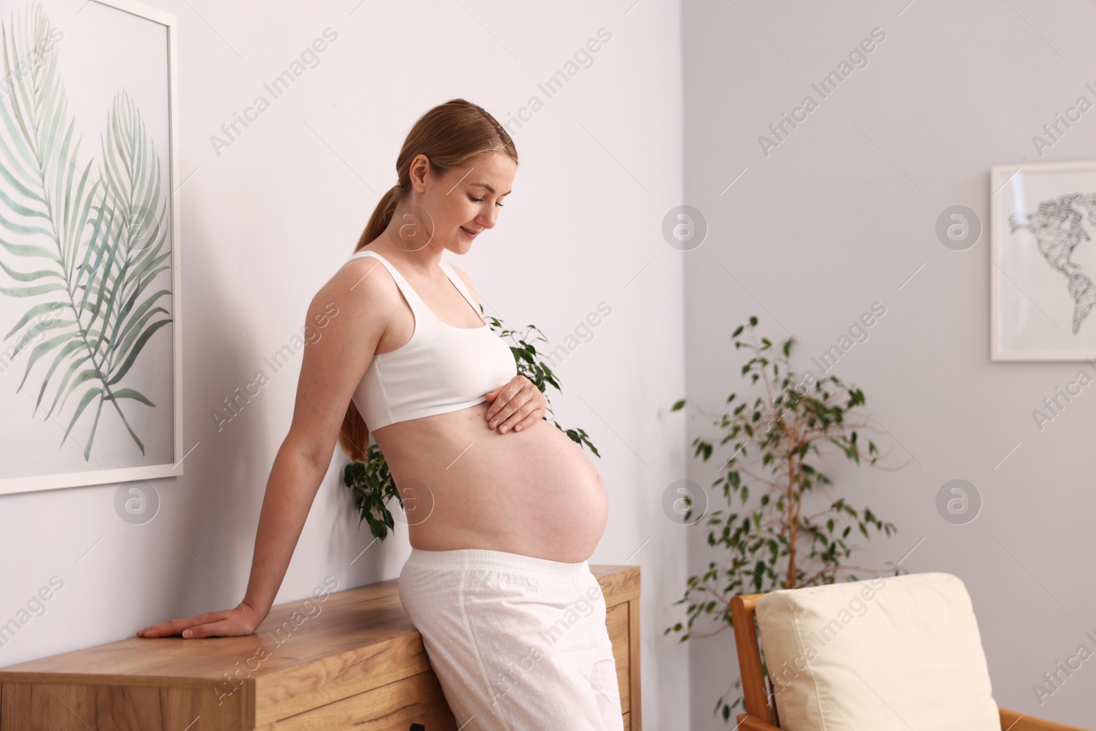 Beautiful pregnant woman touching her belly at home. Space for text Photo of Beautiful pregnant woman touching her belly at home. Space for text