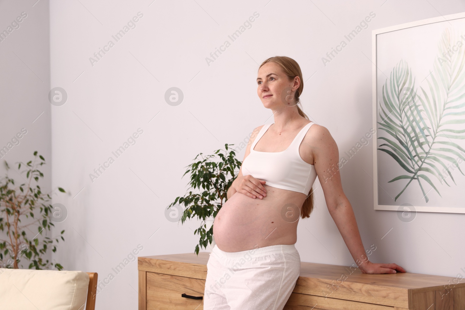 Beautiful pregnant woman touching her belly at home. Space for text Photo of Beautiful pregnant woman touching her belly at home. Space for text