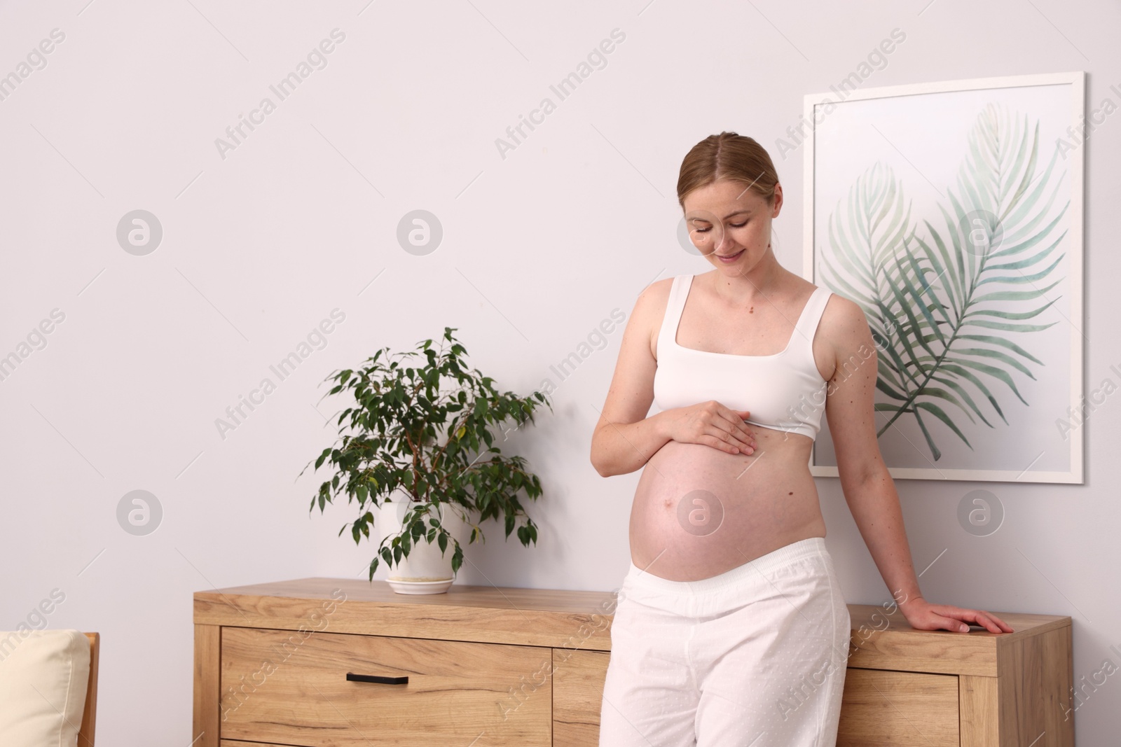 Beautiful pregnant woman touching her belly at home. Space for text Photo of Beautiful pregnant woman touching her belly at home. Space for text