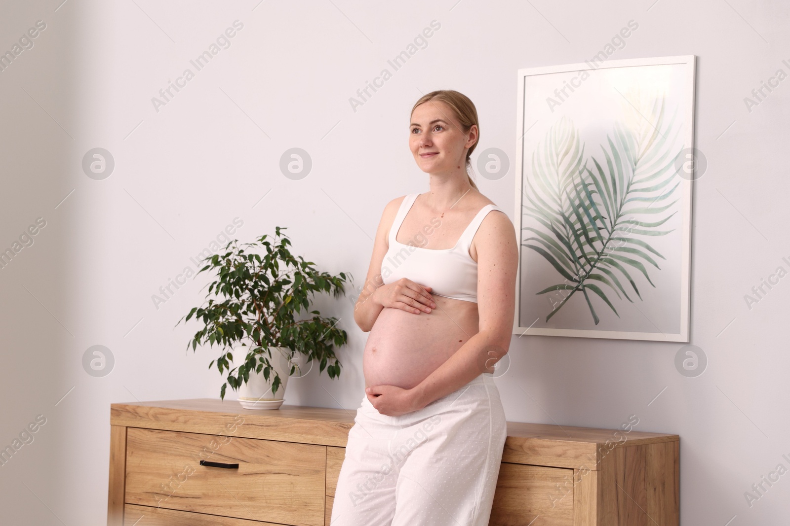 Beautiful pregnant woman touching her belly at home. Space for text Photo of Beautiful pregnant woman touching her belly at home. Space for text