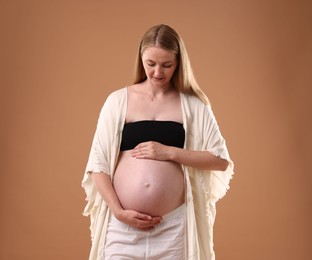 Photo of Beautiful pregnant woman on light brown background