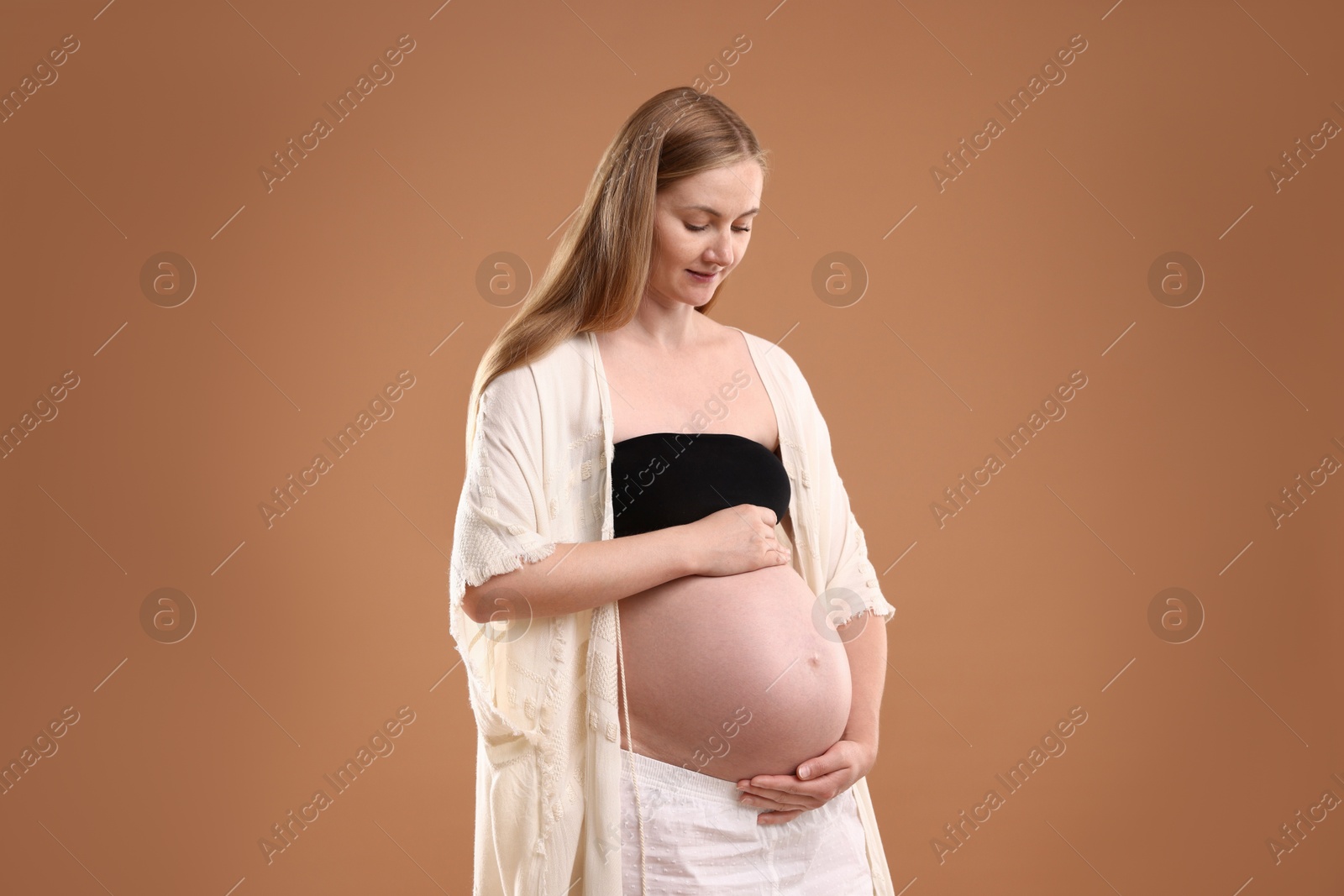 Beautiful pregnant woman on light brown background Photo of Beautiful pregnant woman on light brown background