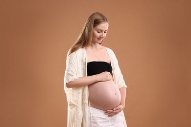 Photo of Beautiful pregnant woman on light brown background