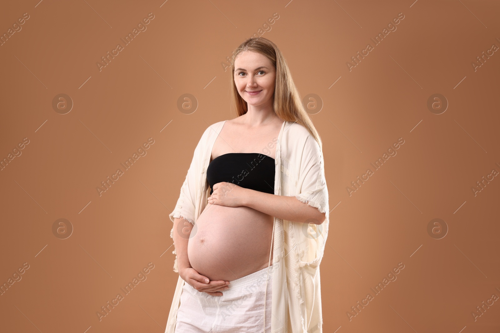 Beautiful pregnant woman on light brown background Photo of Beautiful pregnant woman on light brown background