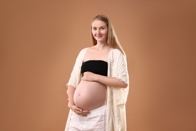 Photo of Beautiful pregnant woman on light brown background