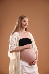 Photo of Beautiful pregnant woman on light brown background