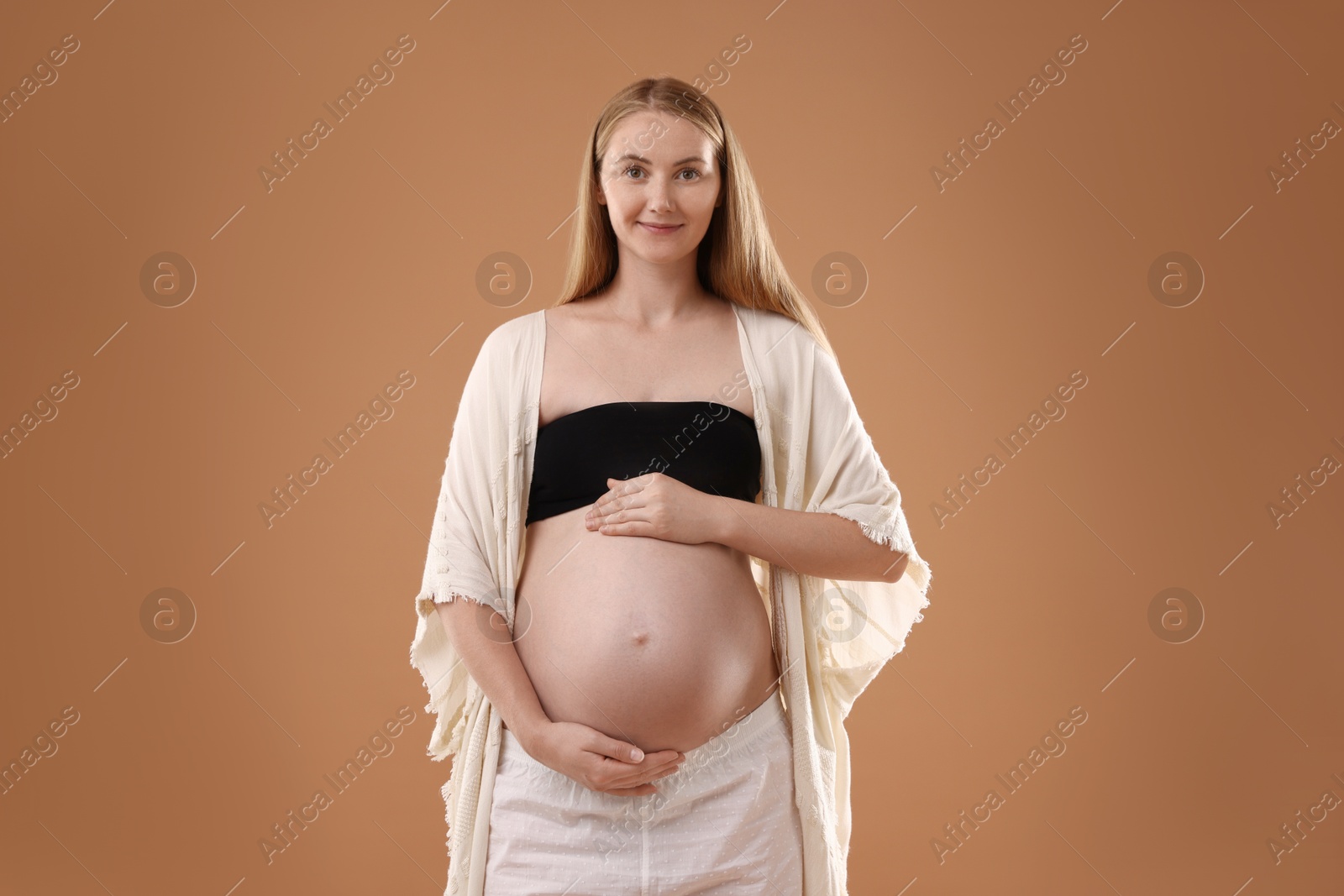 Beautiful pregnant woman on light brown background Photo of Beautiful pregnant woman on light brown background