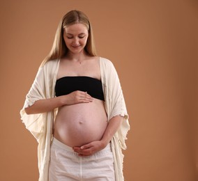 Photo of Beautiful pregnant woman on light brown background