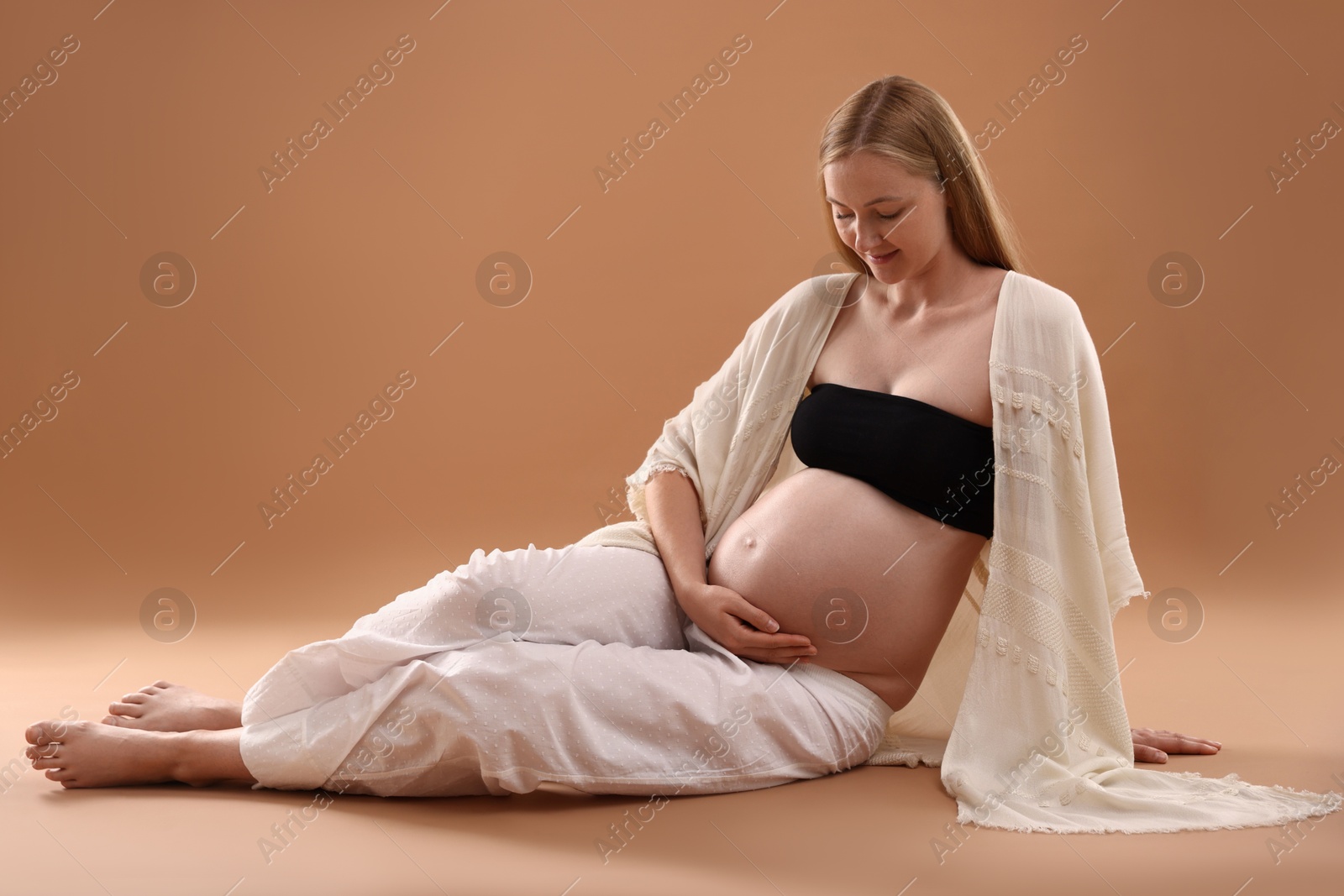 Beautiful pregnant woman on light brown background Photo of Beautiful pregnant woman on light brown background