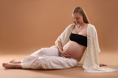 Photo of Beautiful pregnant woman on light brown background