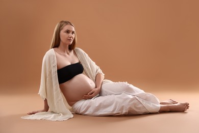 Photo of Beautiful pregnant woman on light brown background