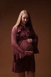 Photo of Beautiful pregnant woman in dress on brown background