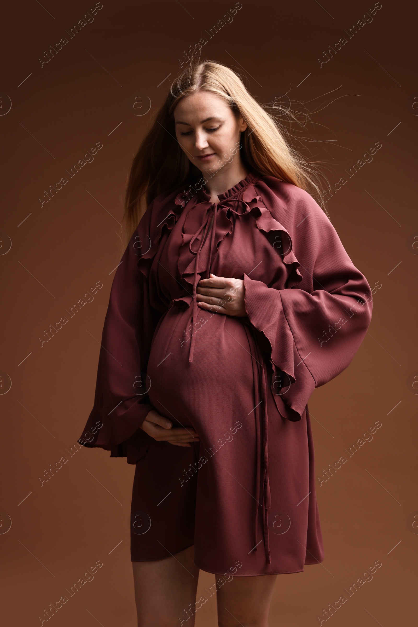Beautiful pregnant woman in dress on brown background Photo of Beautiful pregnant woman in dress on brown background